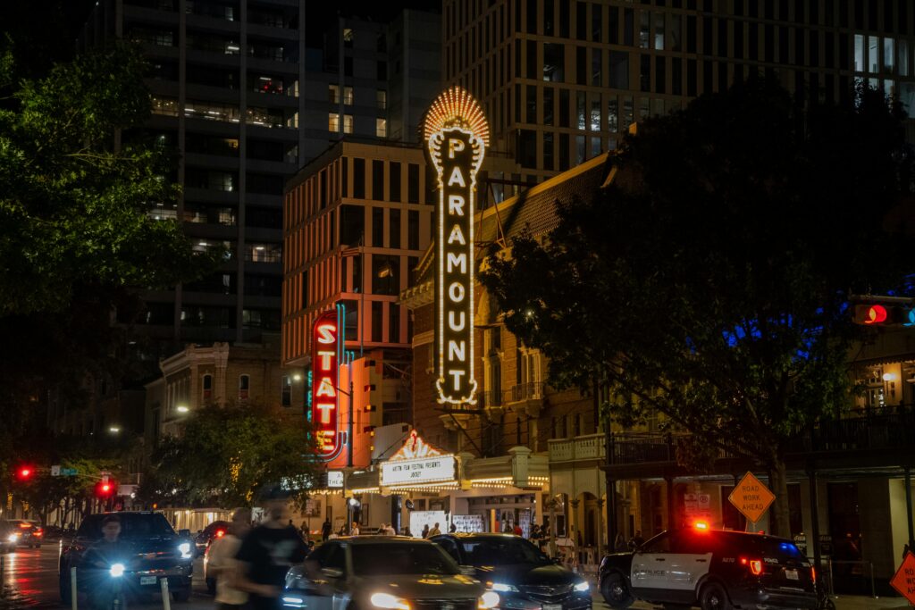 Bustling city street scene at Paramount Theater in Austin, TX during night.