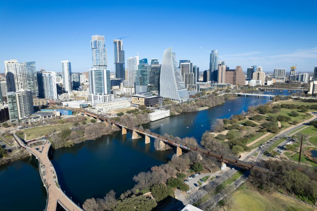 Aerial view of Austin, Texas skyline with landmarks including river and footbridge.